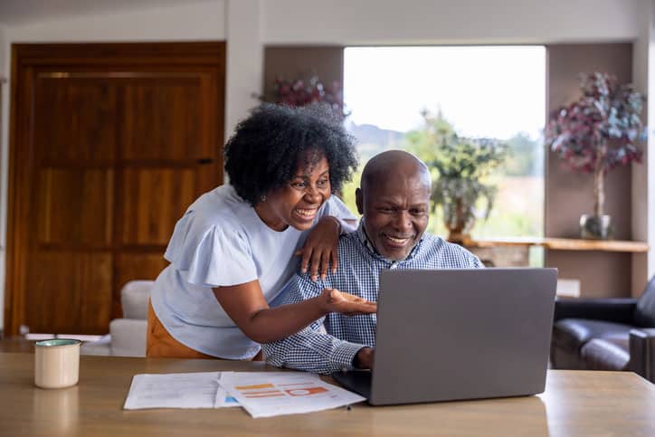 Happy couple reviewing coverage during open season using their laptop